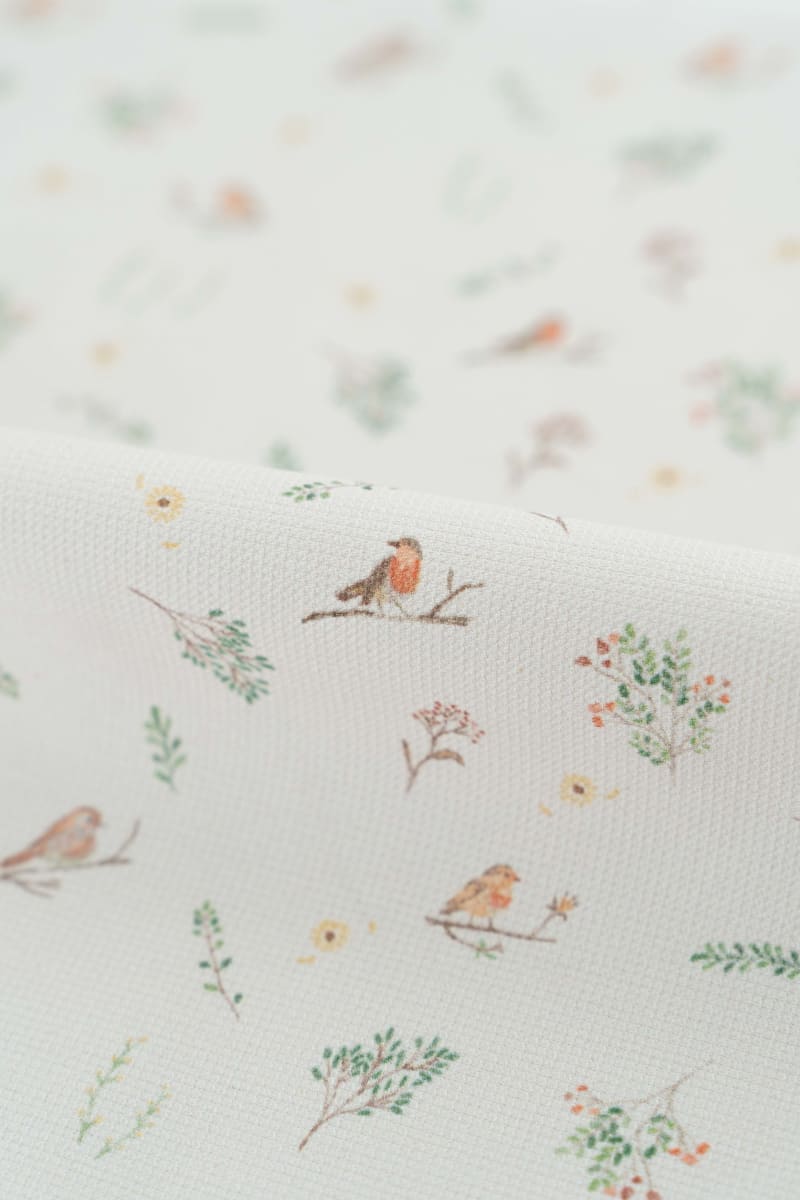 Tejido con estampado infantil de pajaros y flores en tonos suaves y pastel.