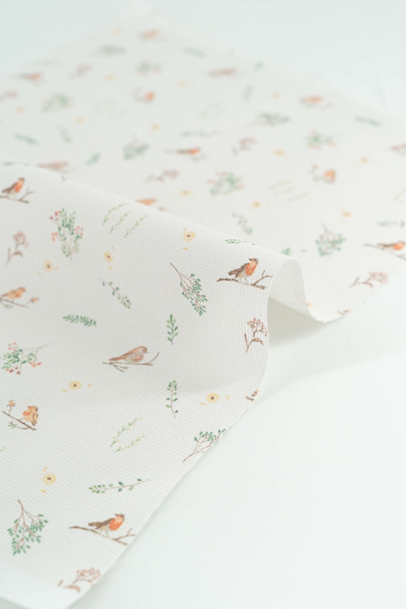 Tejido con estampado infantil de pajaros y flores en tonos suaves y pastel.