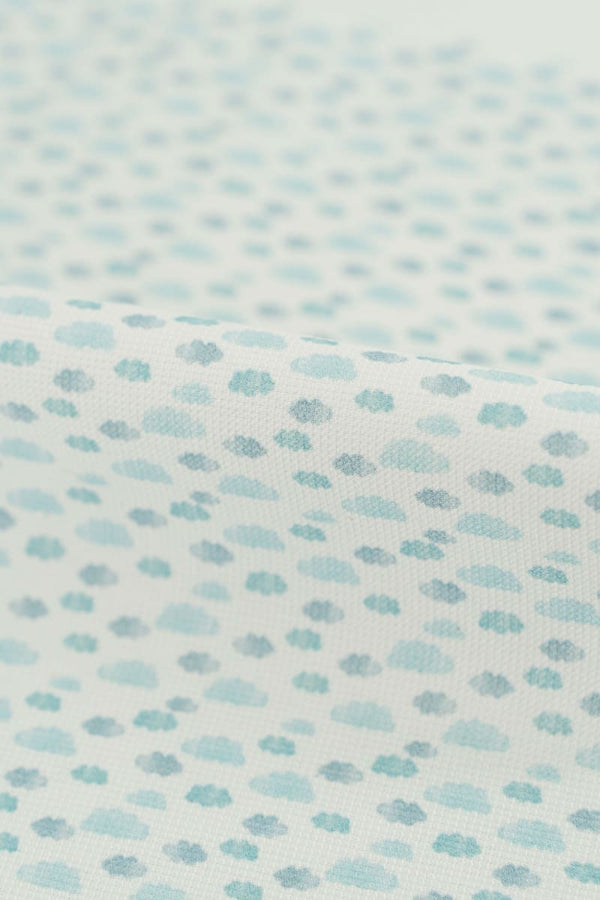 Tejido con estampado infantil de nubes en tonos azules suaves y pastel. 