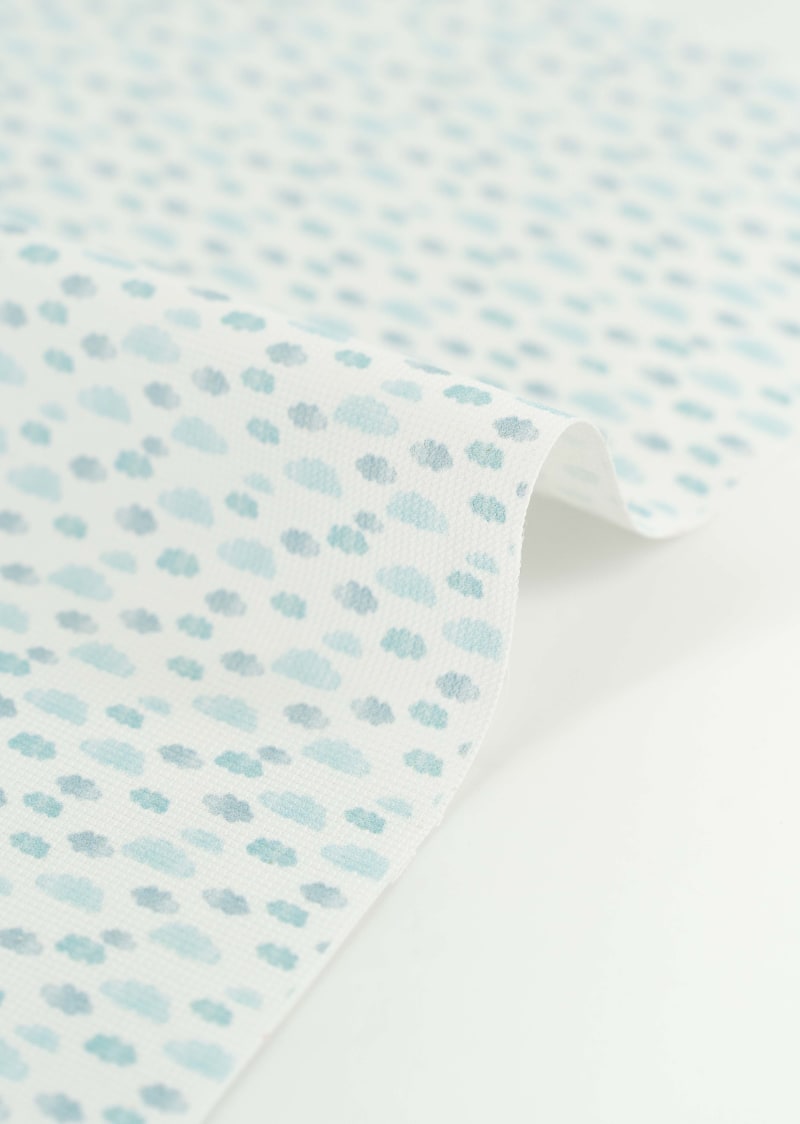 Tejido con estampado infantil de nubes en tonos azules suaves y pastel. 