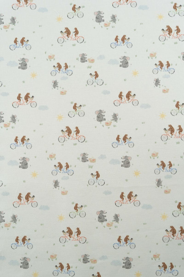 Tejido con estampado infantil de osos montando en bicicleta y lefantes de picnic.