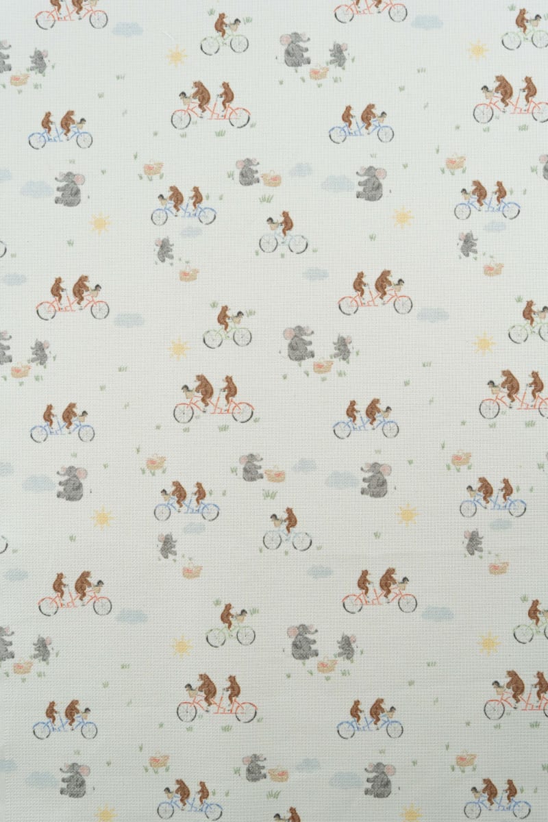 Tejido con estampado infantil de osos montando en bicicleta y lefantes de picnic.