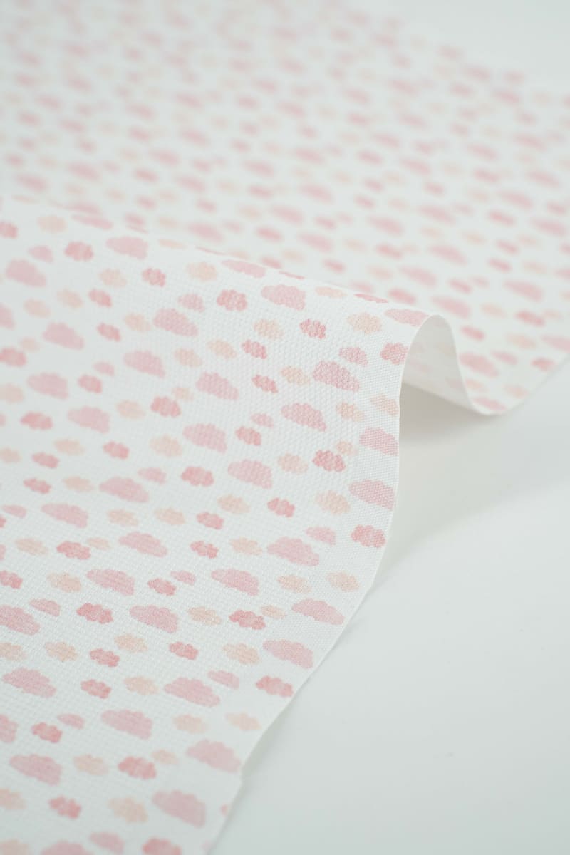 Tejido infantil con estampado de nubes rosas. 