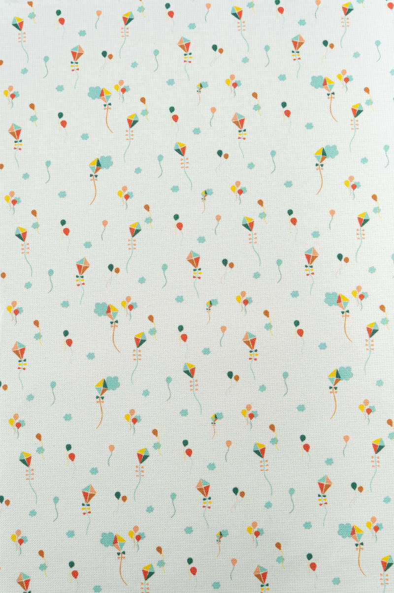 Tejido infantil con estampado de cometas de colores.