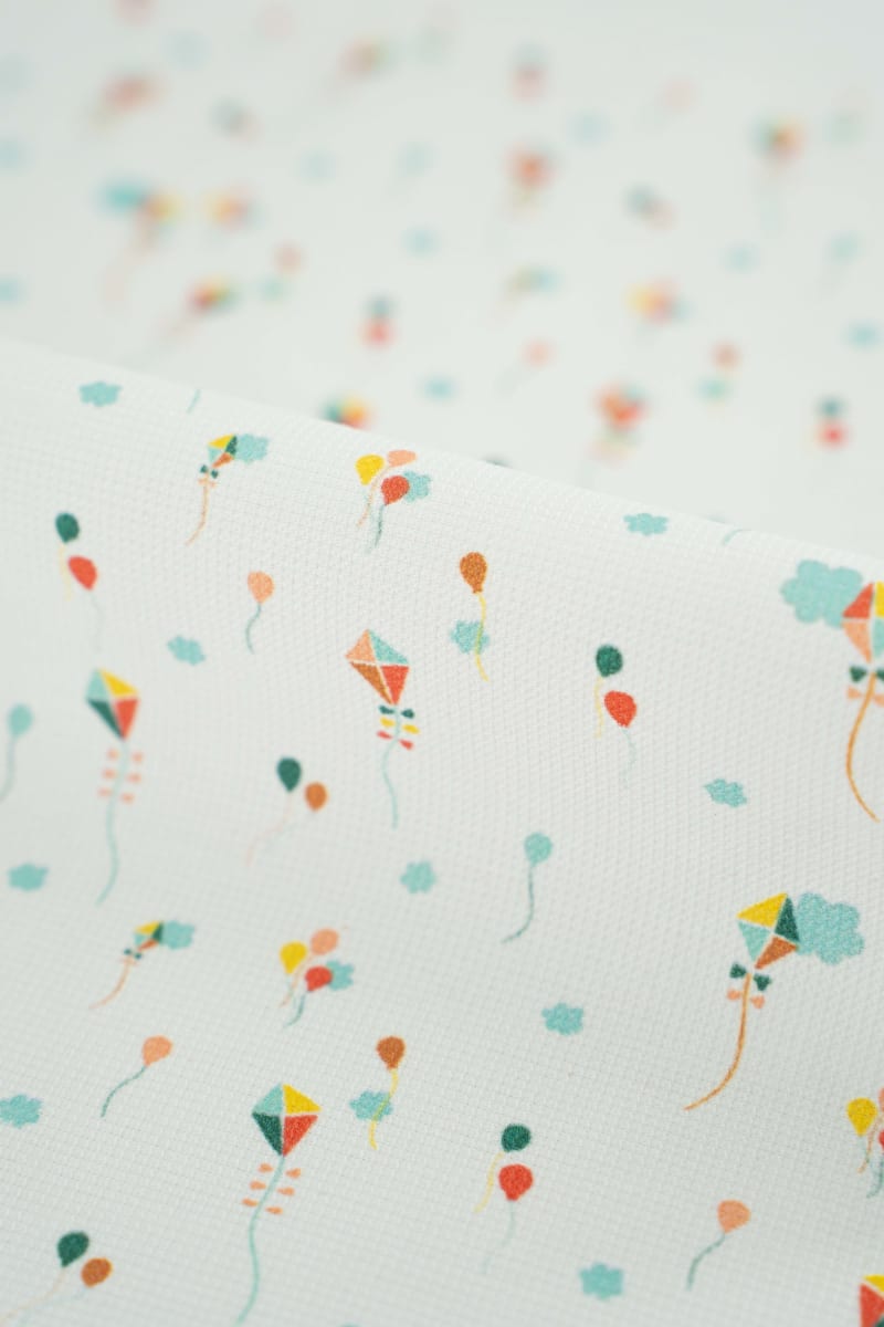 Tejido infantil con estampado de cometas de colores.
