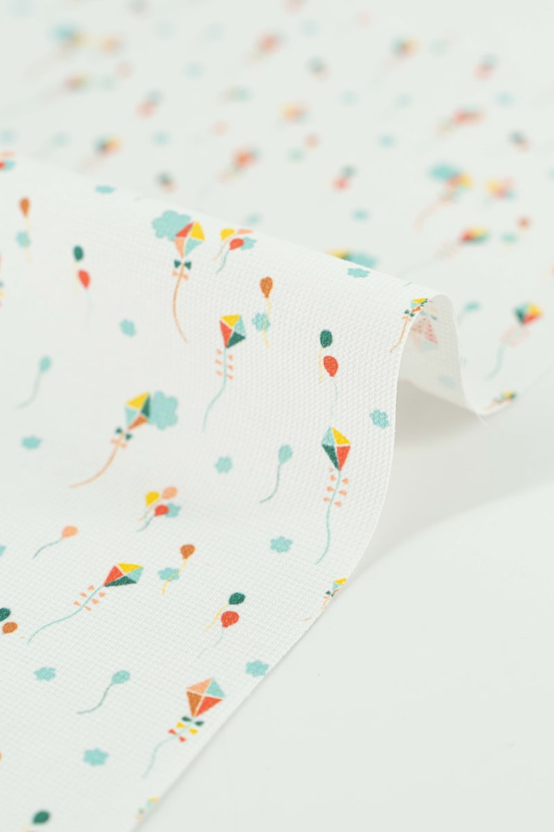 Tejido infantil con estampado de cometas de colores.