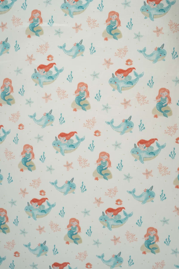 Tejido infantil con estampado de sirenas y motivos marinos.