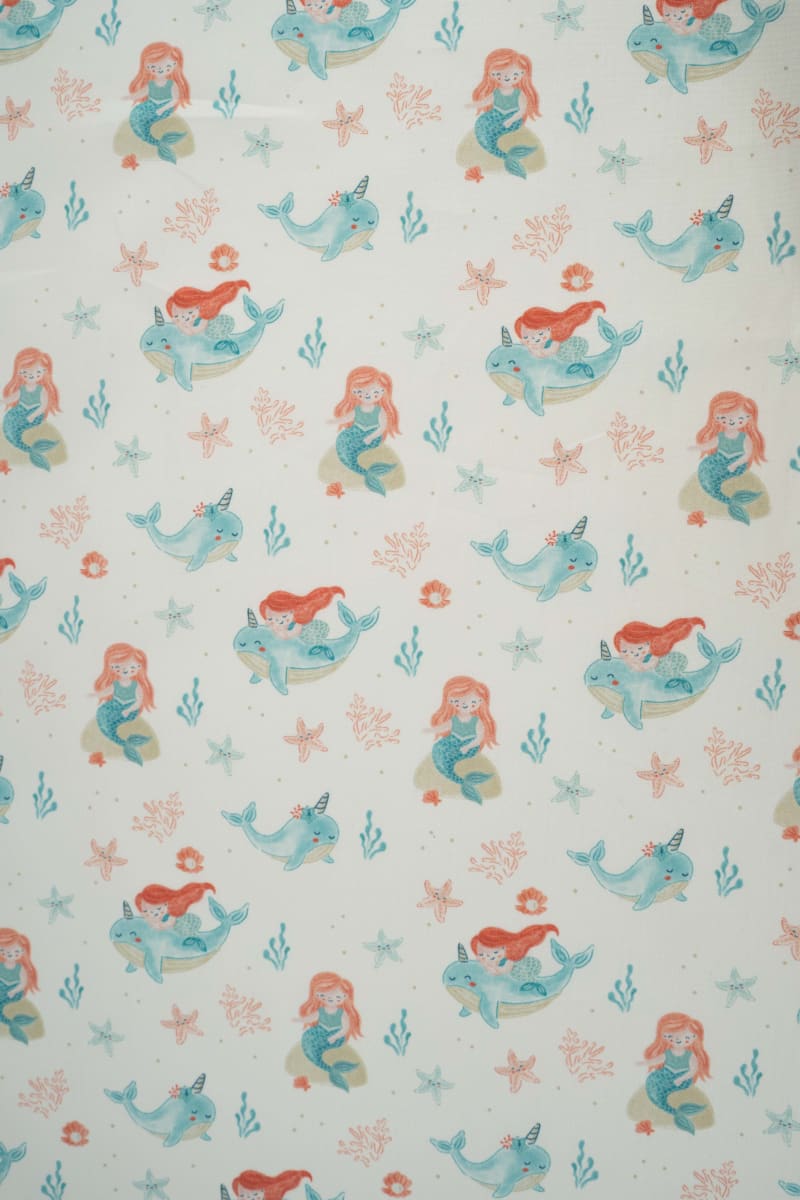 Tejido infantil con estampado de sirenas y motivos marinos.
