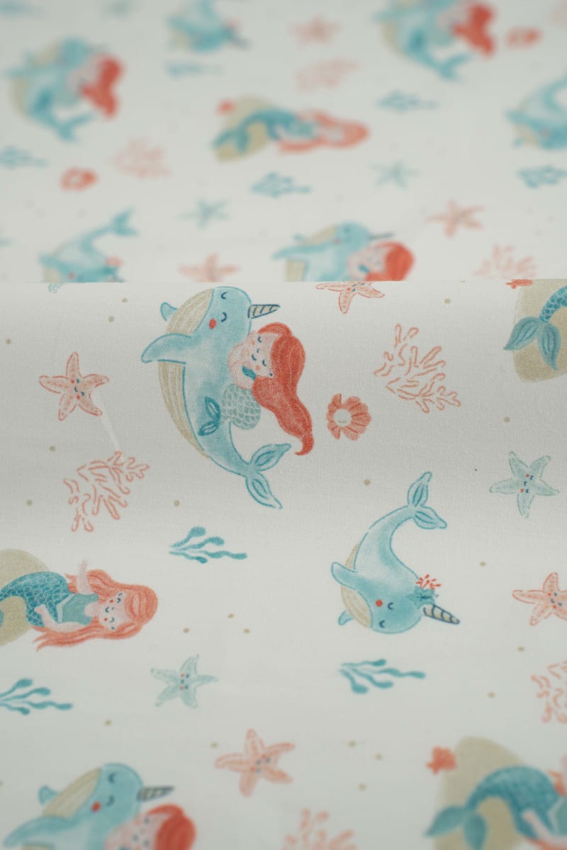 Tejido infantil con estampado de sirenas y motivos marinos.