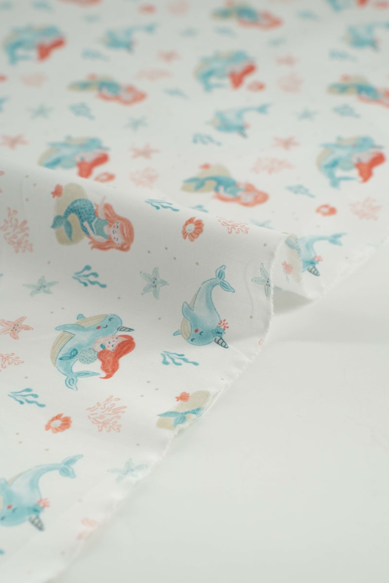 Tejido infantil con estampado de sirenas y motivos marinos.