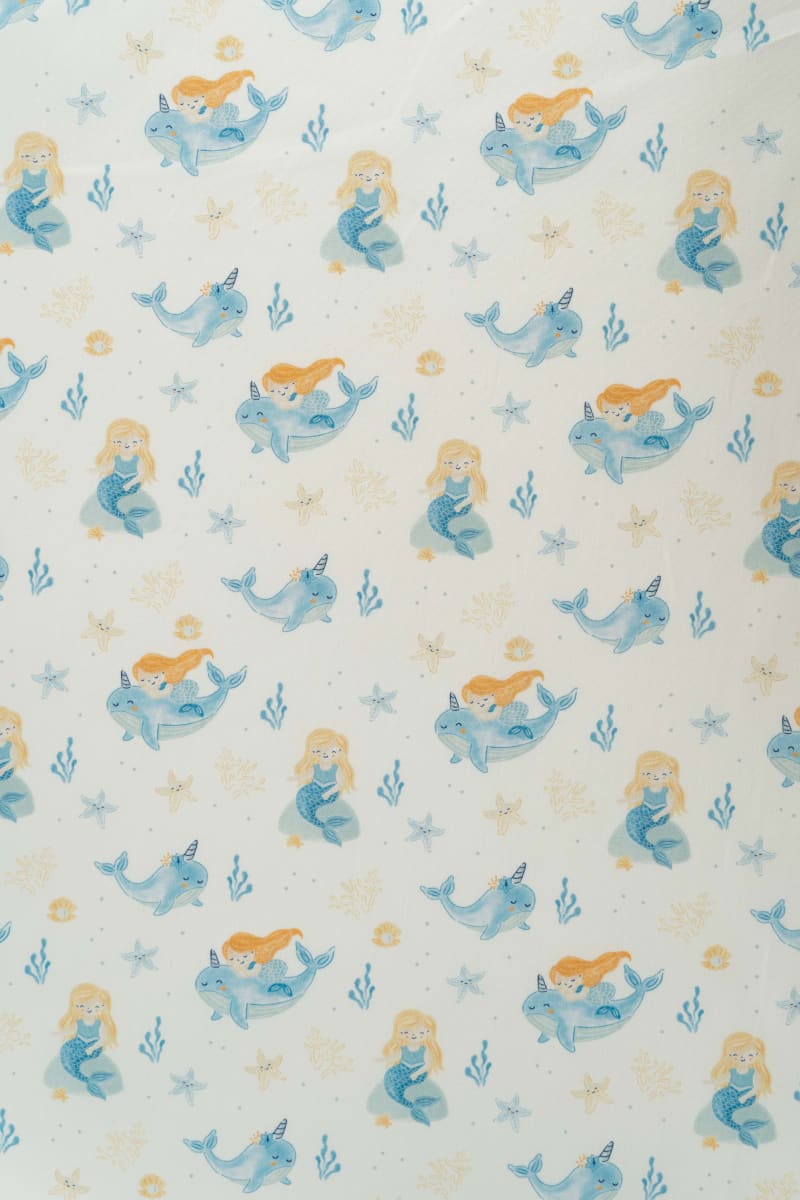 Tejido infantil con estampado de sirenas y motivos marinos.