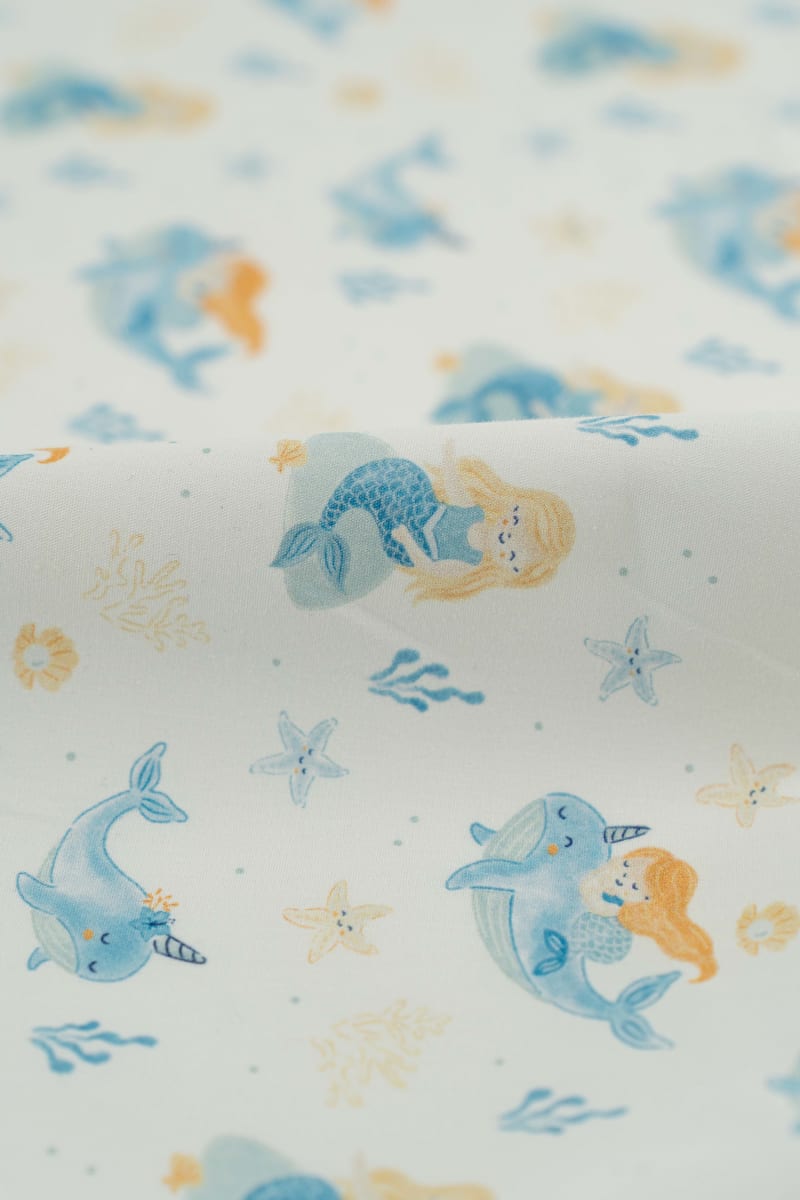 Tejido infantil con estampado de sirenas y motivos marinos.