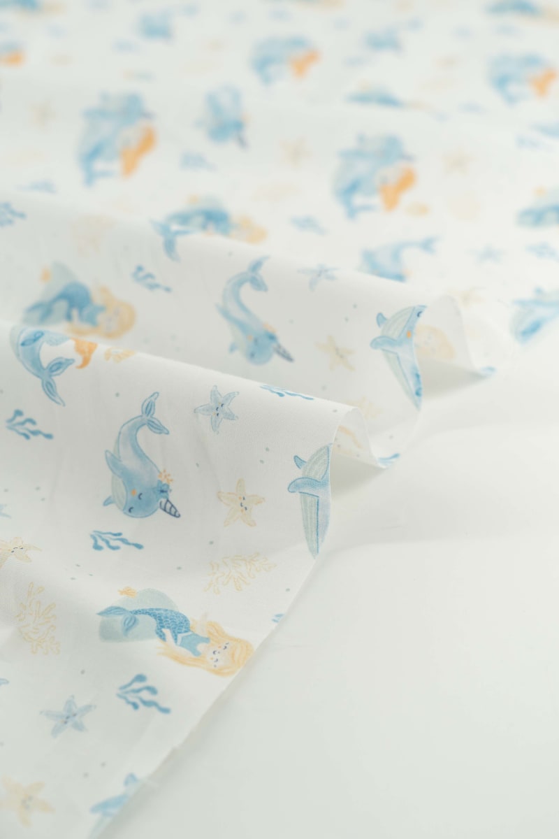 Tejido infantil con estampado de sirenas y motivos marinos.